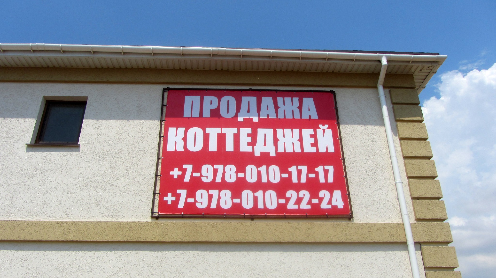 Красный баннер о продаже коттеджей на фасаде здания
